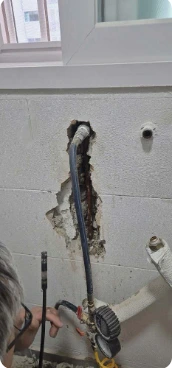작업자가 벽면 배관에 공구를 사용하는 모습